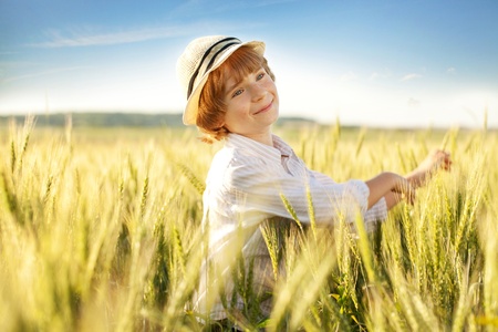 Happy boy with a hat in the middle of wheat fieldsの写真素材