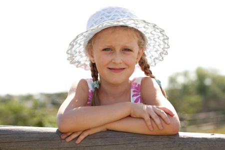 Blue-eyed girl in a wicker hat with braidsの写真素材
