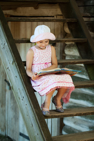 Cute girl in panama, sitting on the stairs reading a book