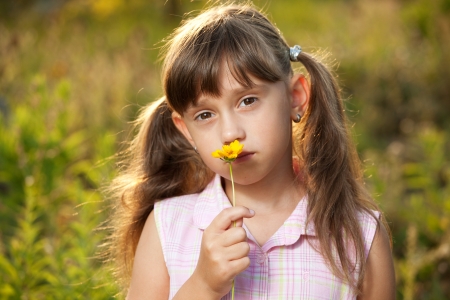 Girl in summer dress holding a yellow flowerの写真素材