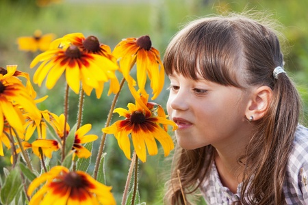 Cute girl with pleasure smell the wildflowersの写真素材