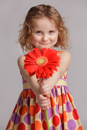 Happy cheerful girl gives a flower to someoneの写真素材