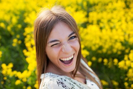 Playful young woman among yellow flowers in a fieldの写真素材