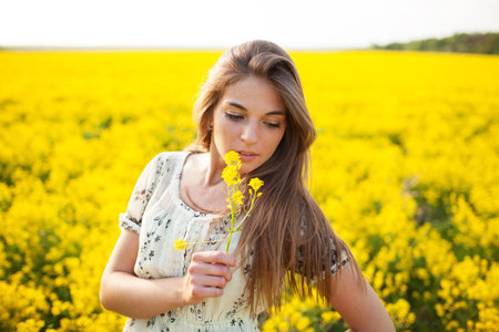 Pretty girl smelling yellow wildflower summer dayの写真素材