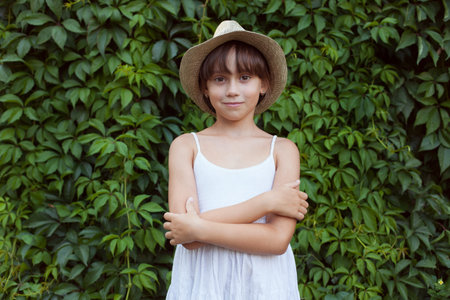 Adorable little girl standing on a background of foliageの写真素材