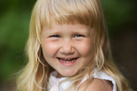 Little happy blond girl in dress smiling funの写真素材