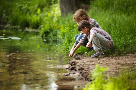 Boy with a girl sitting near the waterの写真素材