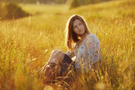 Beautiful young woman sitting in a meadowの写真素材