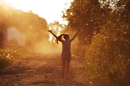 Happy girl running on a dusty road in the summerの写真素材