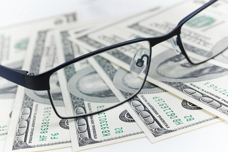 Black glasses lie on the American dollars