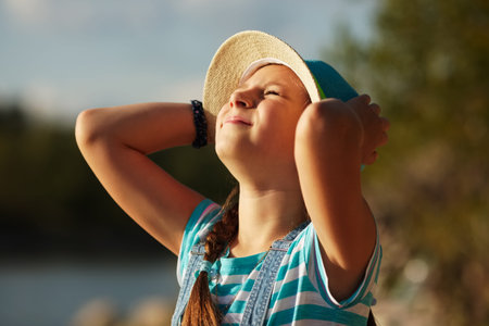 Happy little girl in a hat squinting from the sun