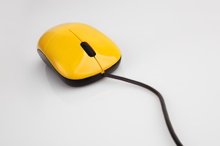 Yellow computer mouse with a black wireの写真素材