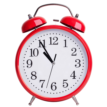 Round red alarm clock is showing almost elevenの写真素材