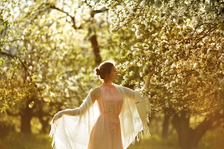 Woman in a pink dress near blooming apple treeの写真素材