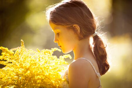 Little girl standing with a bouquet of yellow flowersの写真素材