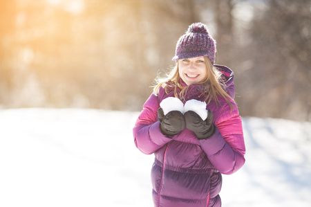 Happy young woman holding two snowballs in her handsの写真素材