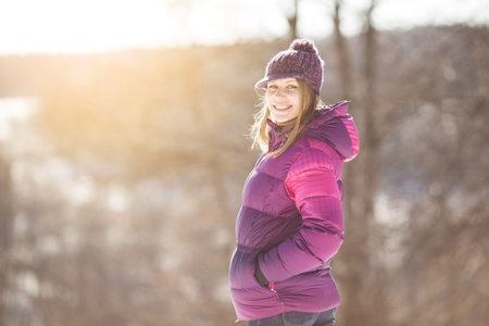 Happy girl in a knitted hat and burgundy jacket in winter