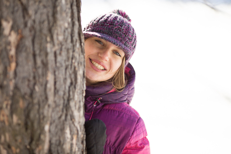 Smiling girl in a hat costs near the treeの写真素材