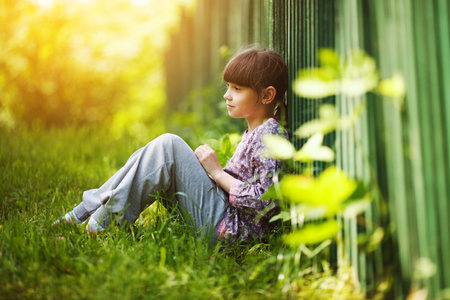 Little happy girl sitting on the grass in summerの写真素材
