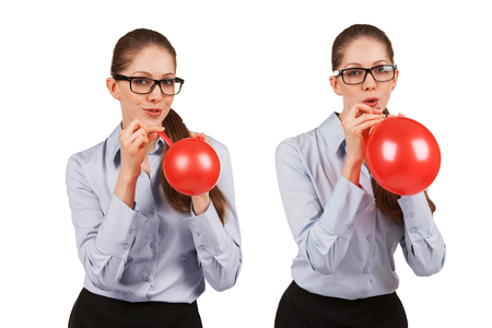 Playful girl with glasses inflates a red balloonの写真素材