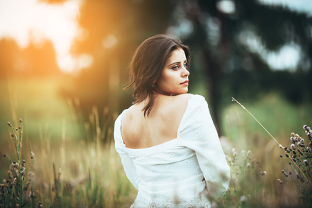 Beautiful dark-haired girl among the field grassの写真素材