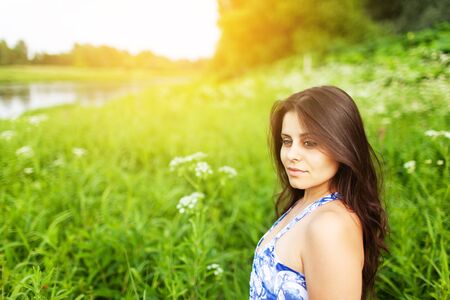 Beautiful dark-haired girl in the middle of a green meadowの写真素材