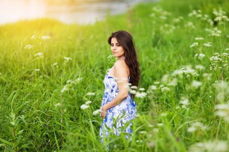 Beautiful sweet girl in blue dress among wildflowersの写真素材