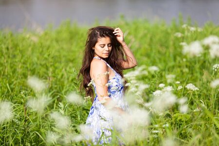 Beautiful sweet woman in blue dress among wildflowersの写真素材