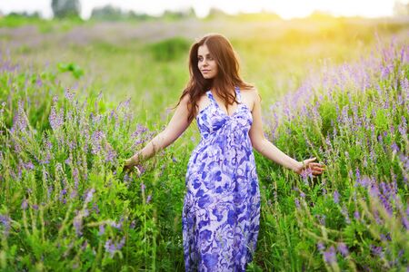 Beautiful dark-haired girl in a dress among wildflowersの写真素材