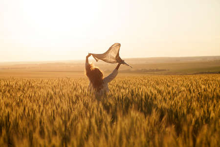 Happy woman with headscarf in the middle of ripe wheat fieldの写真素材