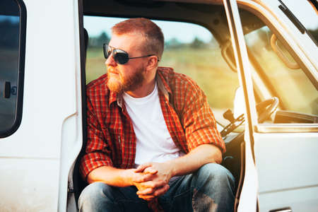 Bearded driver with glasses sits in the cockpit of his carの写真素材