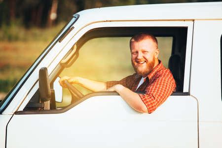 Smiling bearded driver in plaid shirt driving his carの写真素材