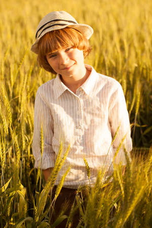 Portrait of a little boy in a hat among the ears of wheatの写真素材