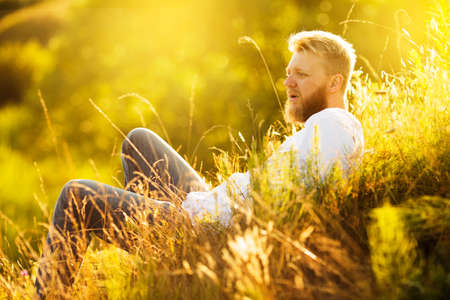 Young man lies and rests in the grass on a meadow in summerの写真素材