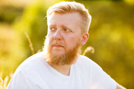 Portrait of a young bearded man in a white t-shirtの写真素材