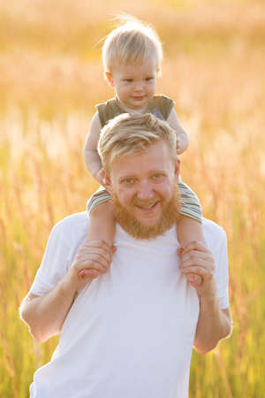 Little son sits on the shoulders of his happy fatherの写真素材