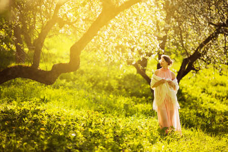 Happy young woman in pink dress in blooming gardenの写真素材