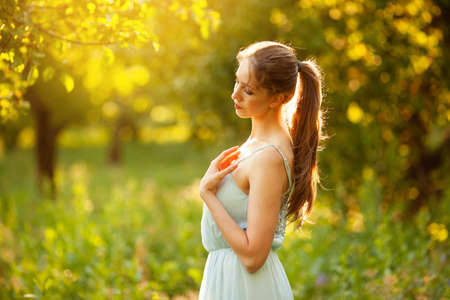 Beautiful young woman in a summer garden in the eveningの写真素材