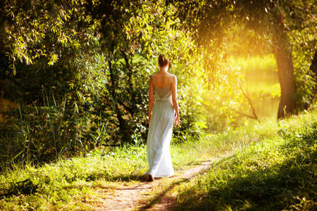 Woman in a blue dress walks in the summer gardenの写真素材