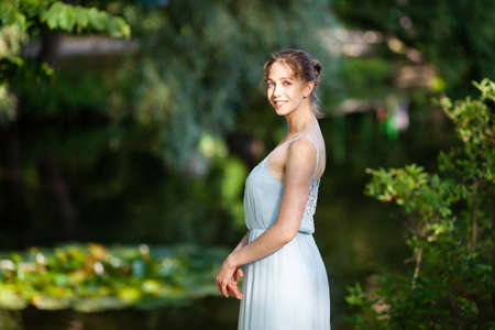 Beautiful young woman in blue dress in the parkの写真素材