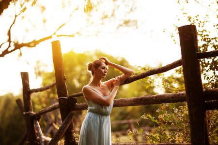 Young pensive woman stands near hedge in the gardenの写真素材