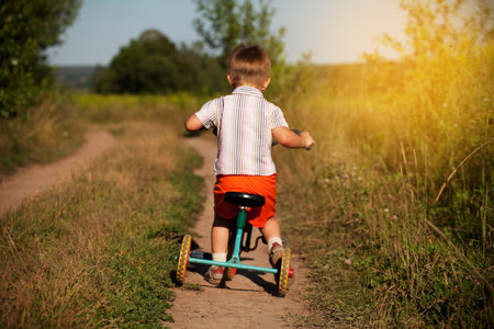 Little boy rides a bicycle on a country roadの写真素材