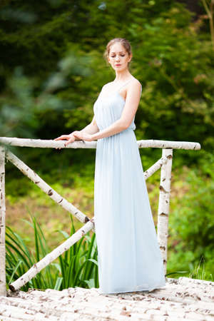 Beautiful young woman in a long blue dressの写真素材