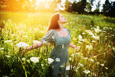Enthusiastic happy woman among wildflowers on a summer dayの写真素材