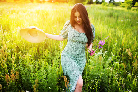 Young woman with hat walks in the field of flowersの写真素材