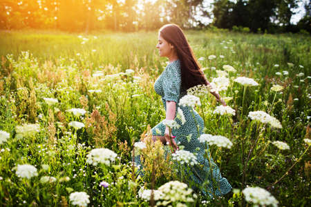 Young happy woman running in a field among flowersの写真素材