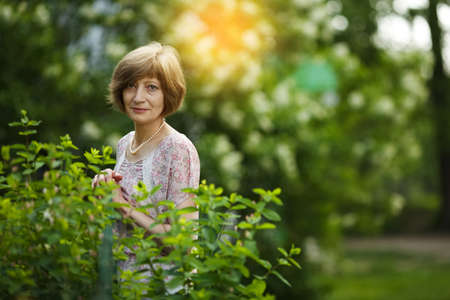 Beautiful slender woman stands in a summer garden near the hedgeの写真素材
