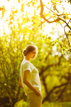 Beautiful slender girl stands in the garden on a sunny dayの写真素材