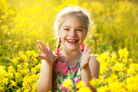 Happy blonde little girl among yellow wildflowersの写真素材