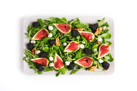 Plate with a salad of figs, blackberries, arugula, mozzarella and walnuts on a white background.の写真素材